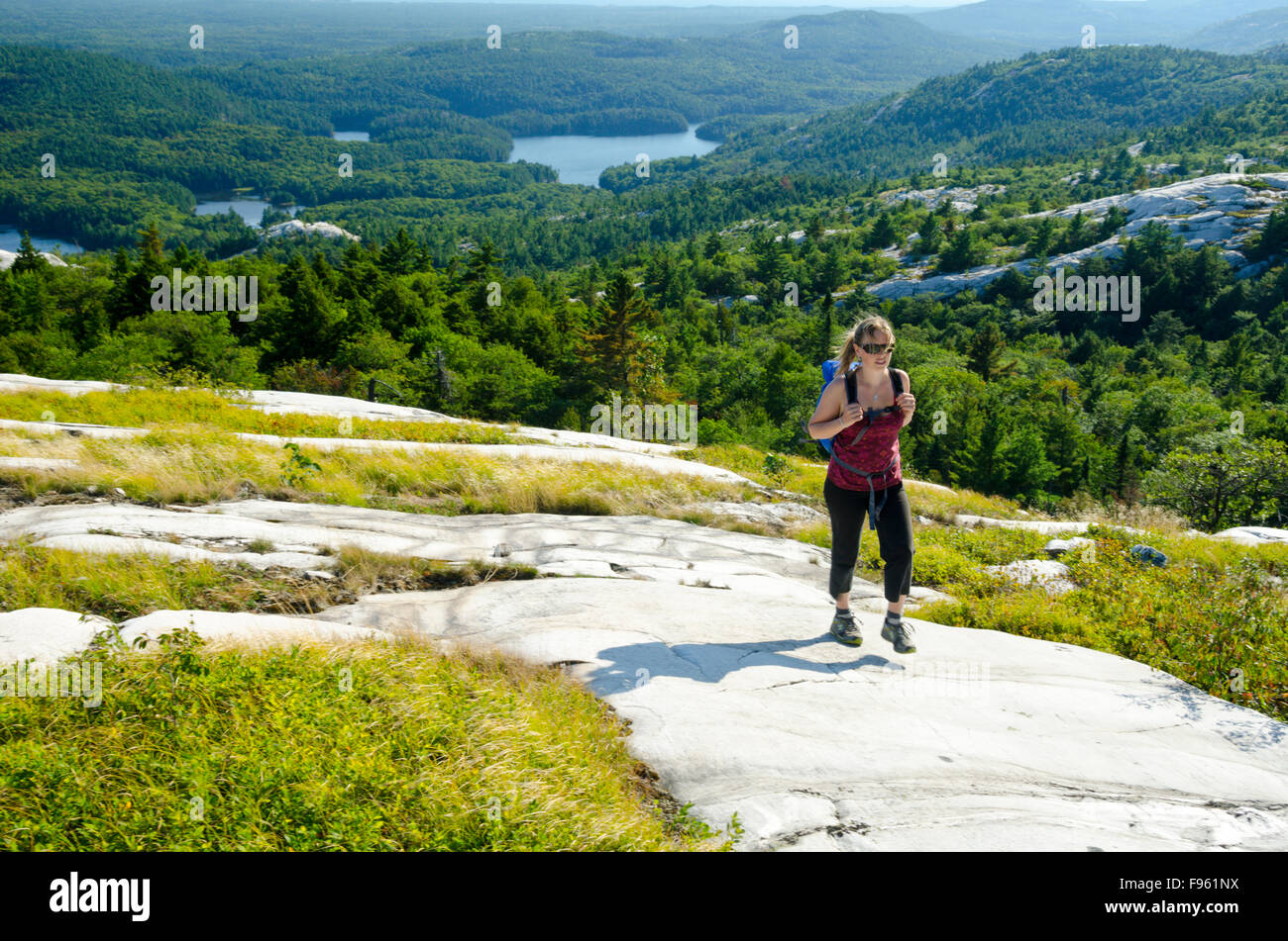A young woman hikes on the skyline atop Silver Peak, the highest mountain in southern Ontario, Killarney Provincial Park Stock Photo
