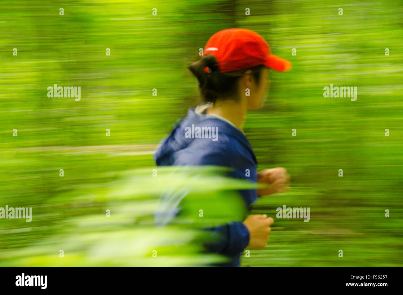 A female jogger floats through the forest in High Park, Toronto, Ontario Stock Photo