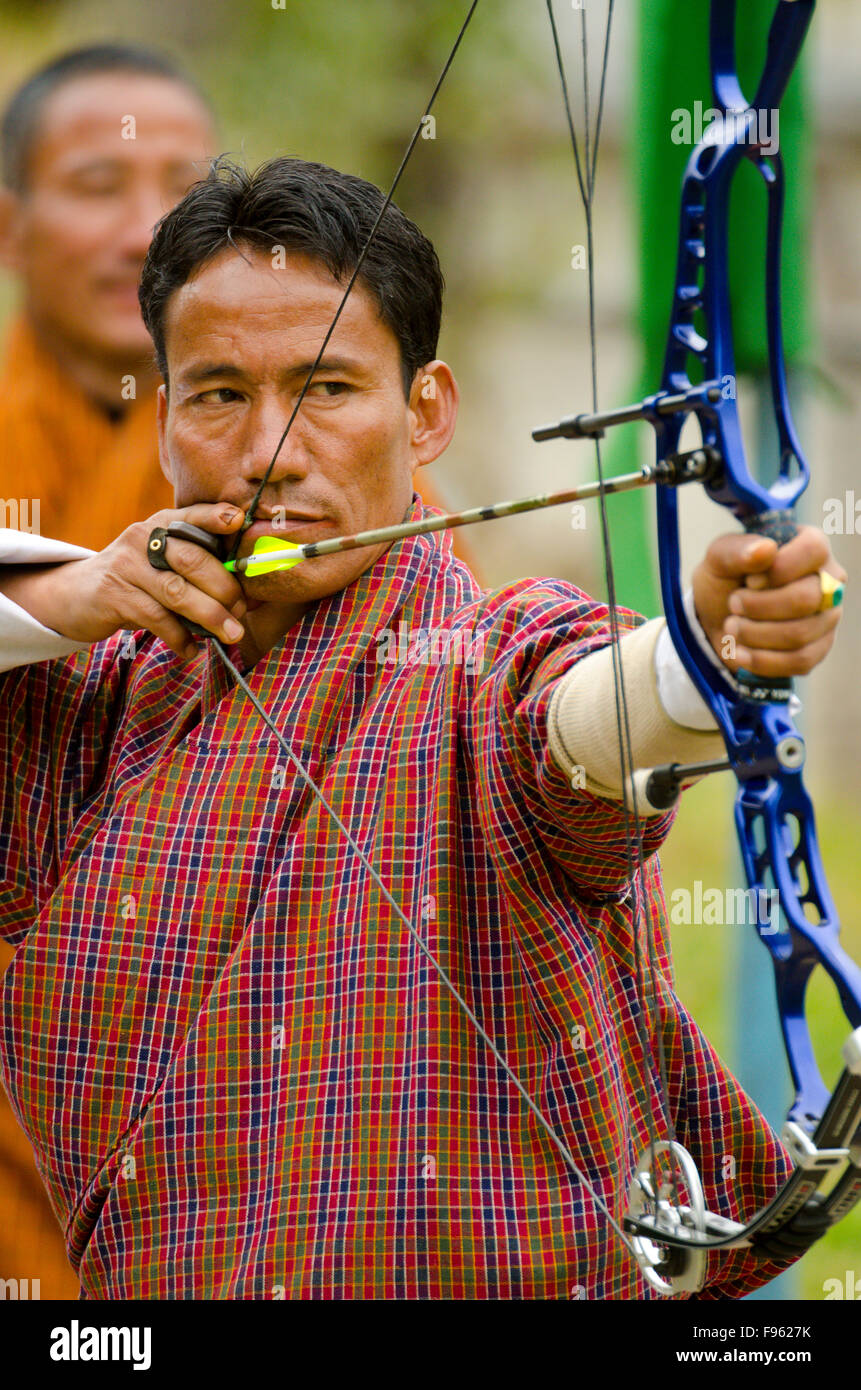 A Buddhist man takes aim with a bow and arrow in Bhutan, where the national sport is archery Stock Photo