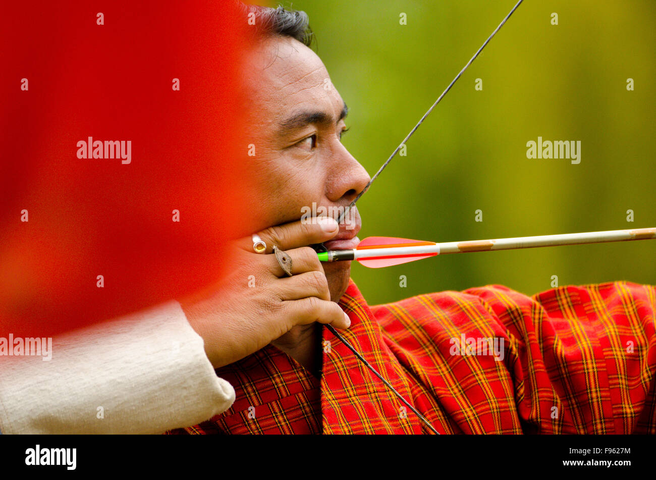 A Buddhist man takes aim with a bow and arrow in Bhutan, where the national sport is archery Stock Photo