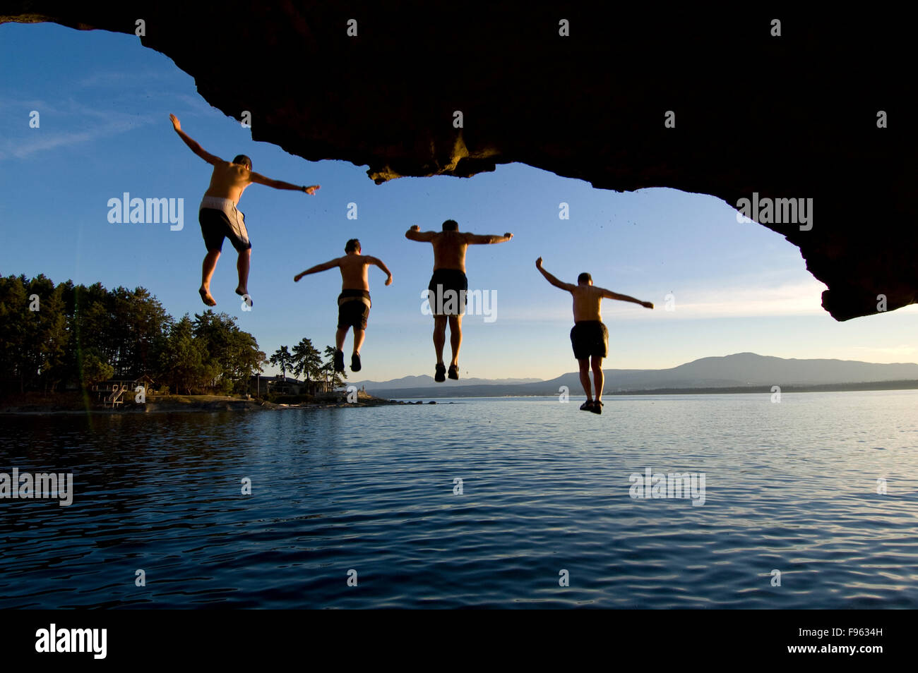Four people jump from the cliffs of the Malaspina Galleries into the Pacific Ocean, Gabriola Island, BC Canada Stock Photo