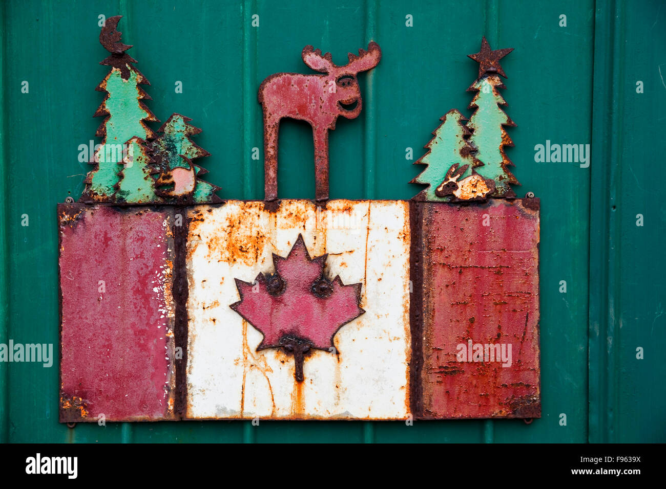 Artisanal rendering of the Canadian flag topped with Canadian fauna and flora, and made of plate metal that has rusted Stock Photo