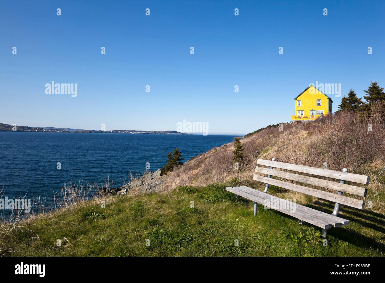 Yellow house and bench overlooking Conception Bay on the outskirts of Cupids, Newfoundland, Canada Stock Photo