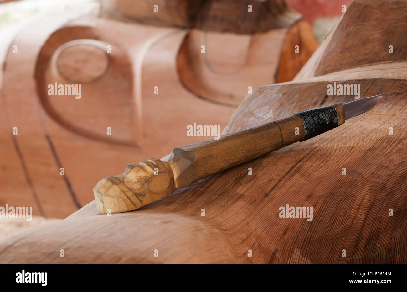 A carving tool rests atop a roughed in Totem Pole, Alert Bay Stock Photo
