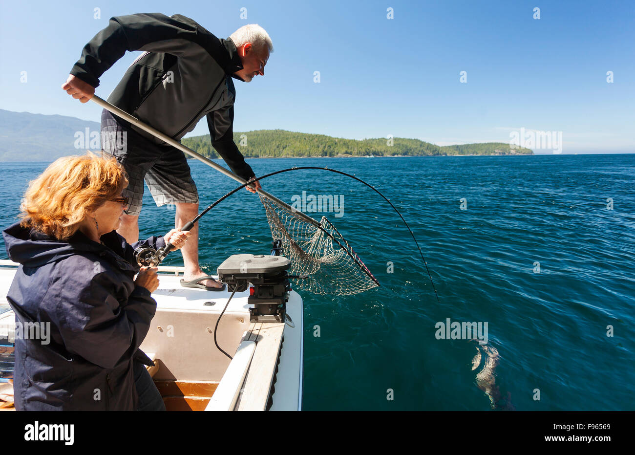 A female angler reels in her prized catch during the telegraph cove fishing derby.  Flower Island Stock Photo