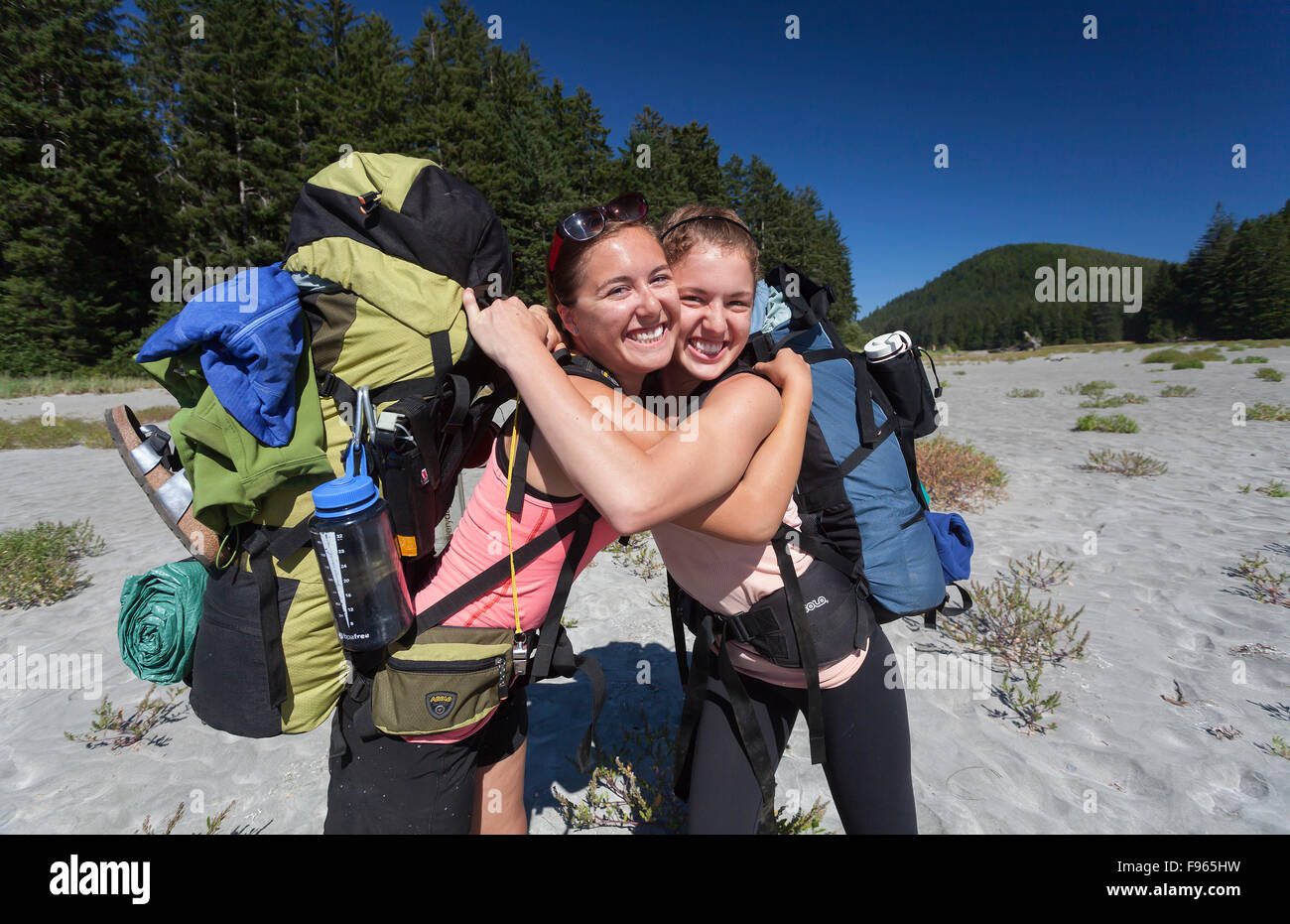 Two sisters hug and enjoy the end of the day's hike arriving at San Josef Bay along the Cape Scott Trail. Stock Photo