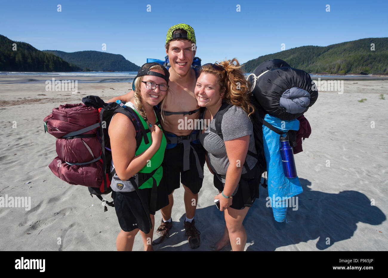 Three friends hiking, hug after arriving at San Josef Bay. Stock Photo