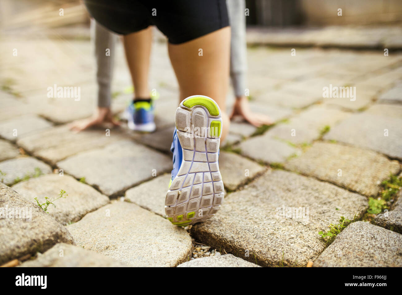 Female runner running on tiled pavement in city center, closeup on