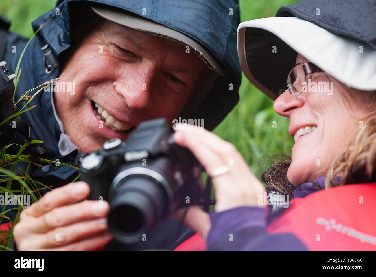 A mature couple inspect an image while photographing among the Sedge Grass in an estuary at the head of Mussel Inlet Stock Photo