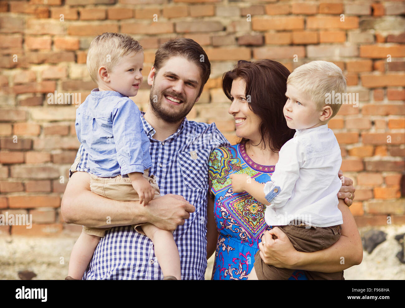 Happy young family have fun together in nature by the old brick house Stock Photo
