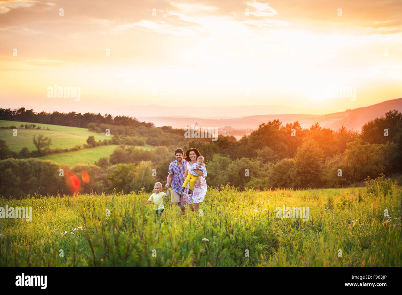 Happy young family have fun together in nature in sunset field Stock Photo