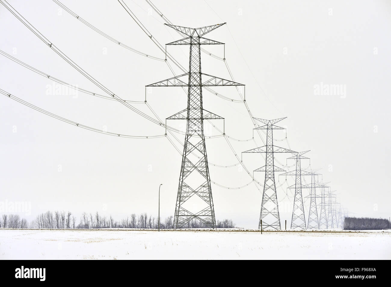 A horizontal landscape image of electricity transmittion lines running through a series of towers carring electric power to Stock Photo