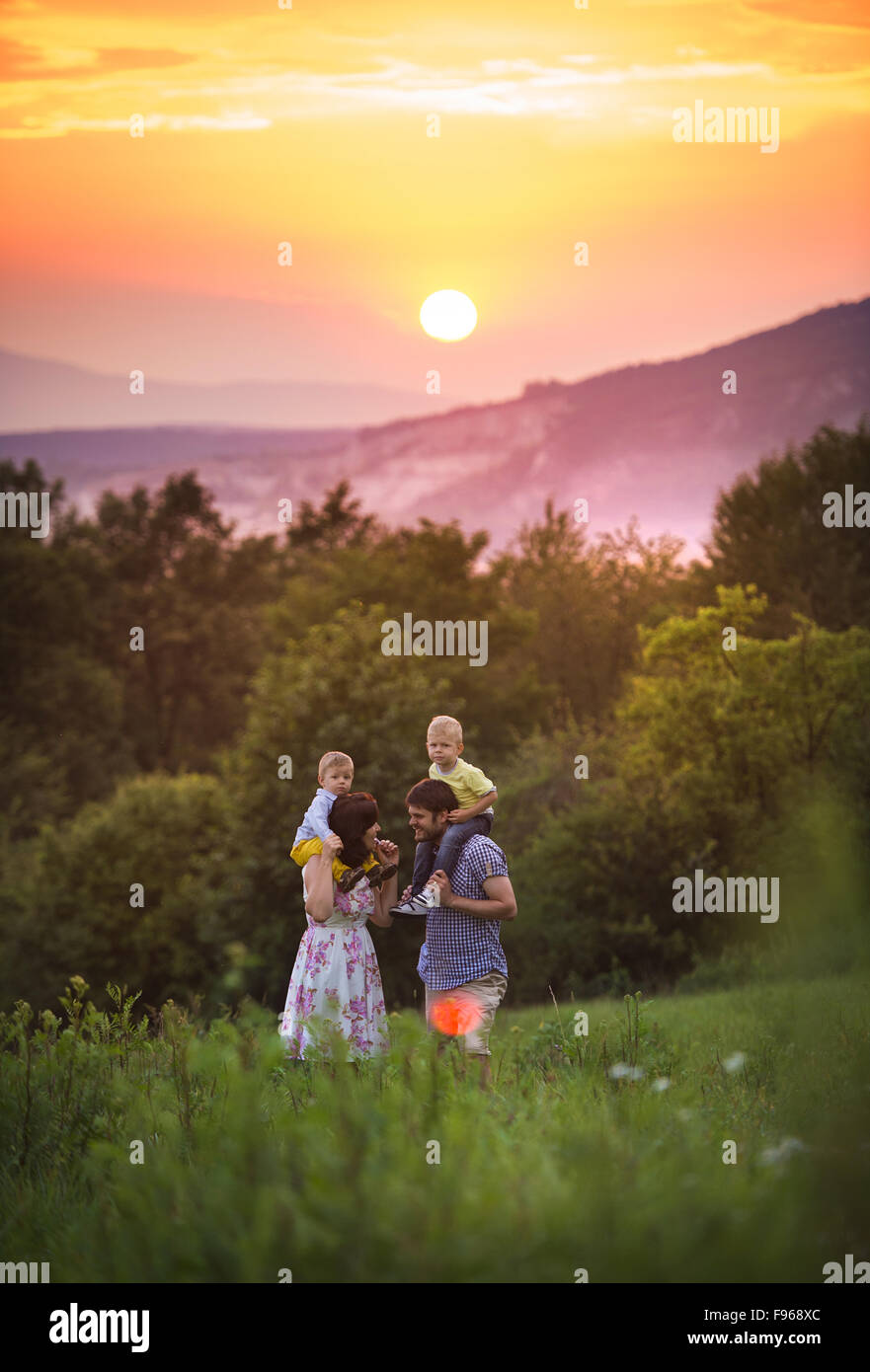 Happy young family have fun together in nature in sunset field Stock Photo