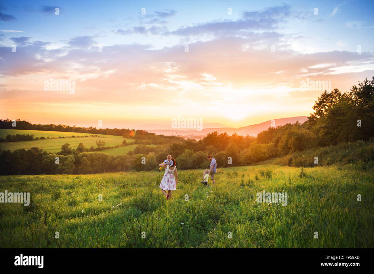 Happy young family have fun together in nature in sunset field Stock Photo