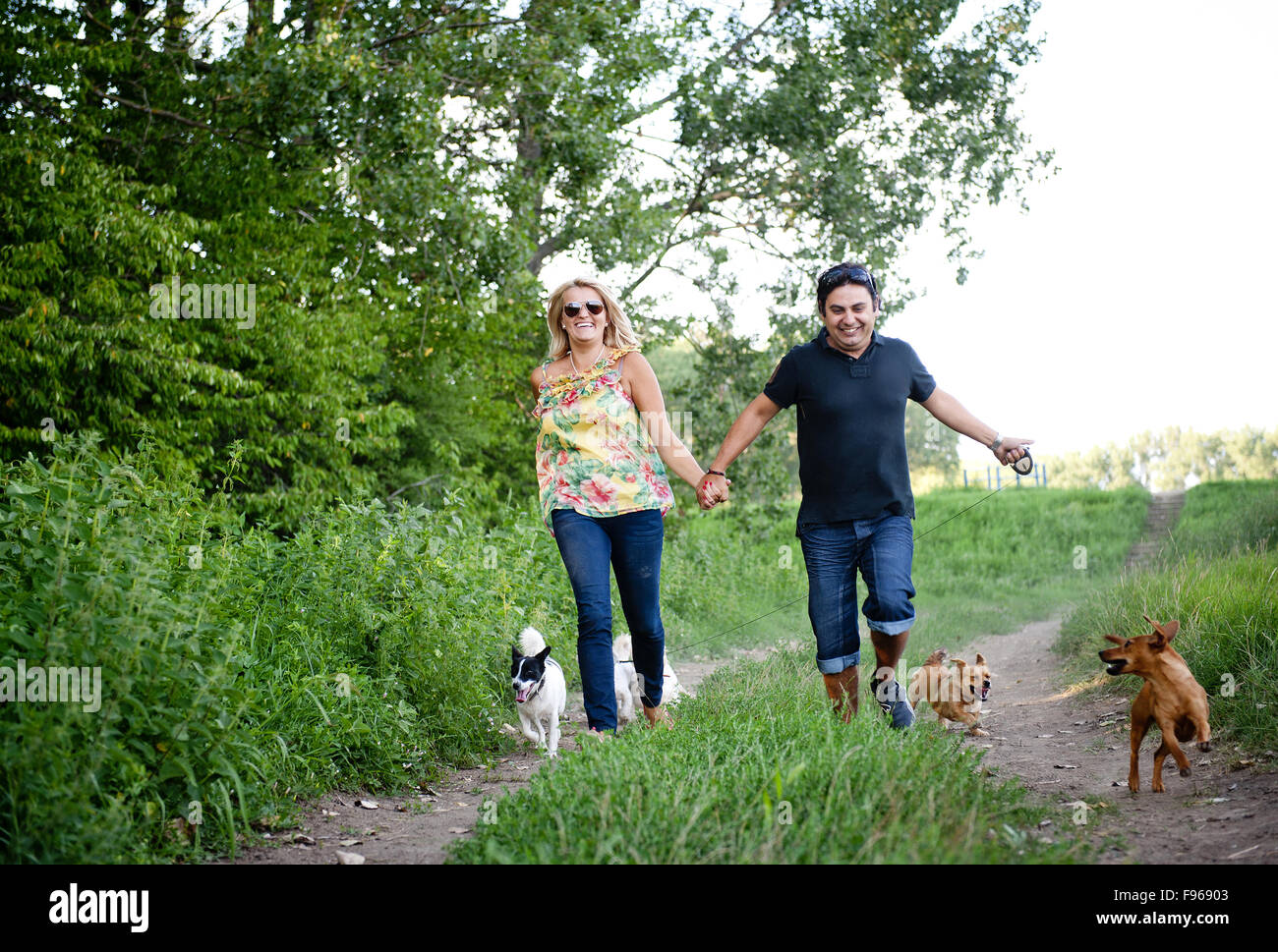 Happy young couple is walking their two dogs in green nature Stock ...