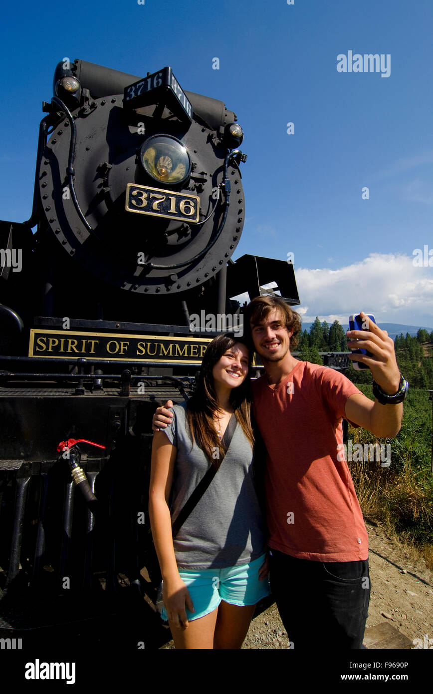 Young couple catch a selfie with the historic Spirit of Summerland, Summerland, in the South Okanagan region of British Stock Photo
