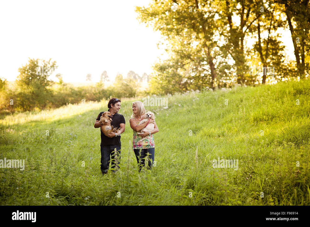 Happy young couple is walking their two dogs in green nature Stock ...