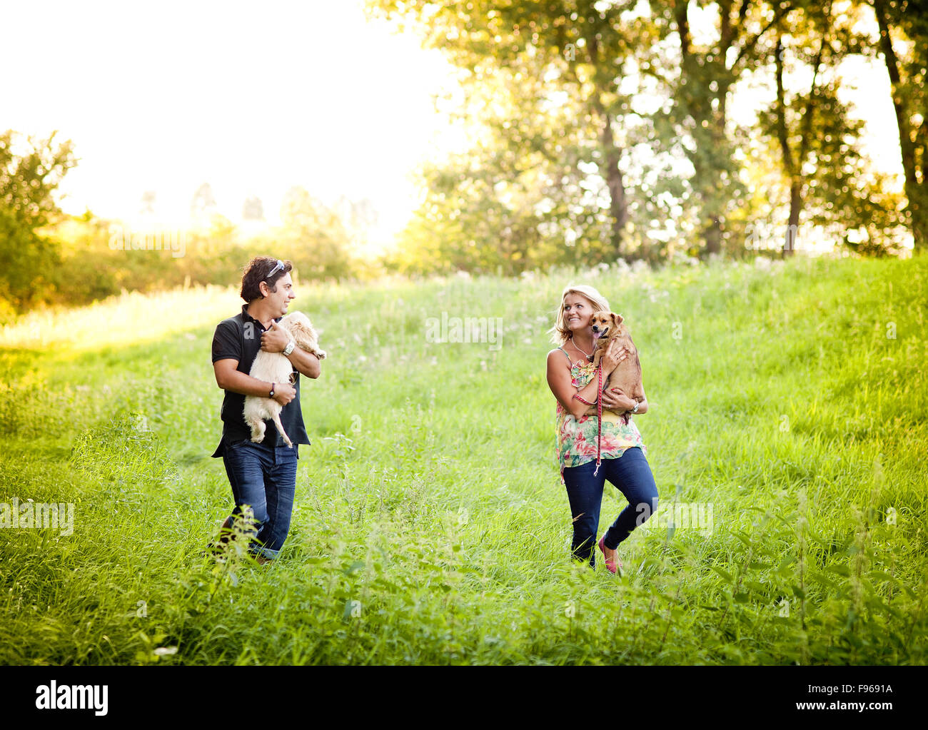 Happy young couple is walking their two dogs in green nature Stock ...