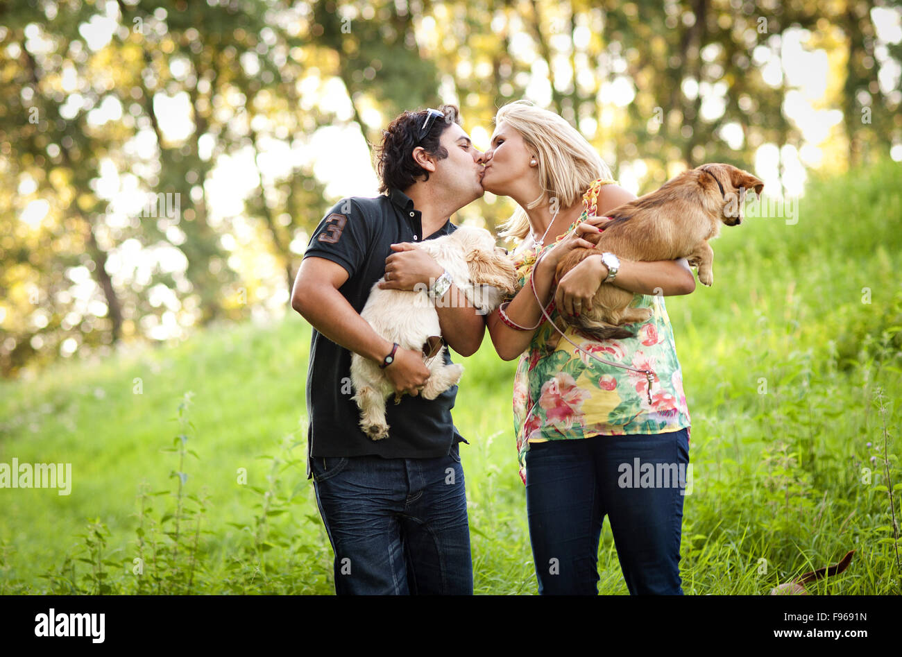 Happy young couple is walking their two dogs in green nature Stock ...