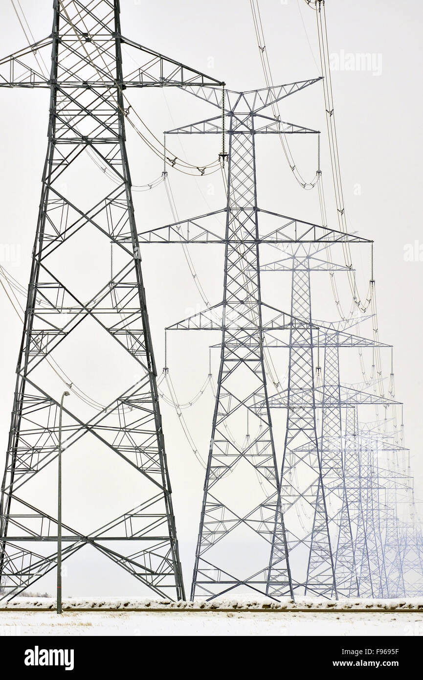 A vertical image of transmittion lines run through a series of steel towers carring electricity to destinationa in Alberta Stock Photo
