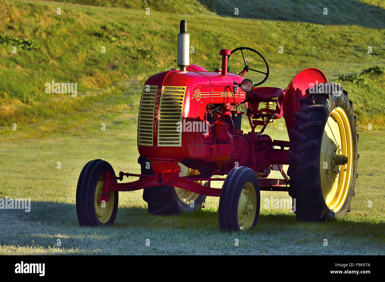 A vintage Cockshutt farm tractor in a rural field bathed by the warming early morning light near Sussex New Brunswick Canada Stock Photo