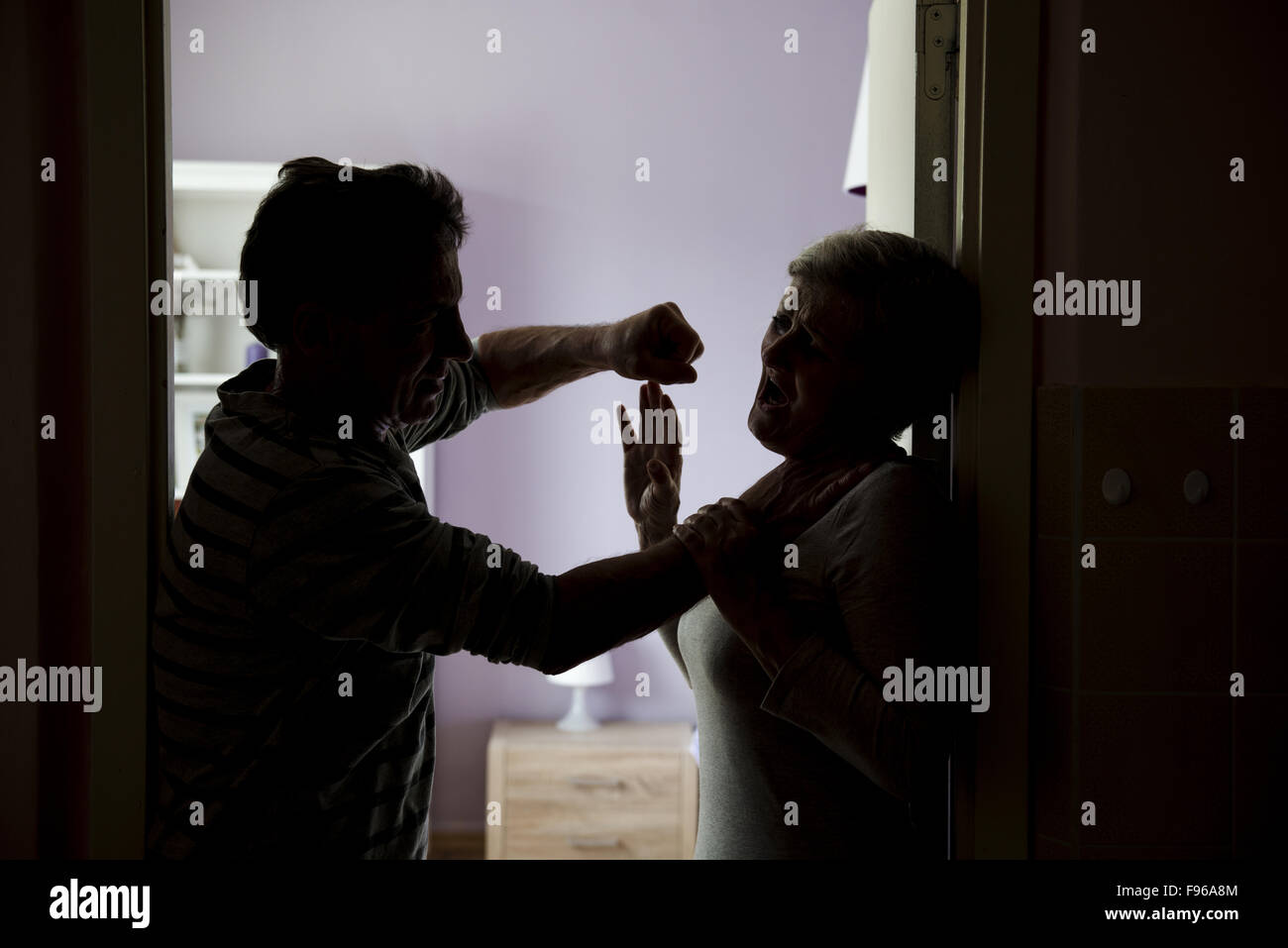 Silhouette of mature couple fighting, the man is physically abusing woman. Woman is victim of domestic violence Stock Photo