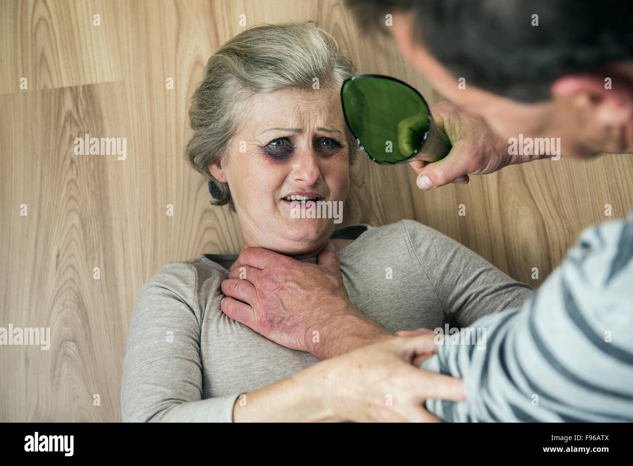 Woman victim of domestic violence and abuse. Mature woman with black eye scared of a man with broken bottle Stock Photo