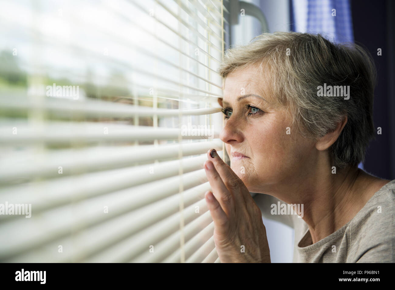 Scared woman is looking through the window. Having bruise on her face Stock Photo