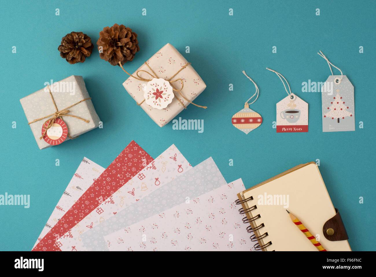 Christmas stationery arrangement of elements top view template. Empty spiral notebook with wrapping paper stack, vintage gift bo Stock Photo