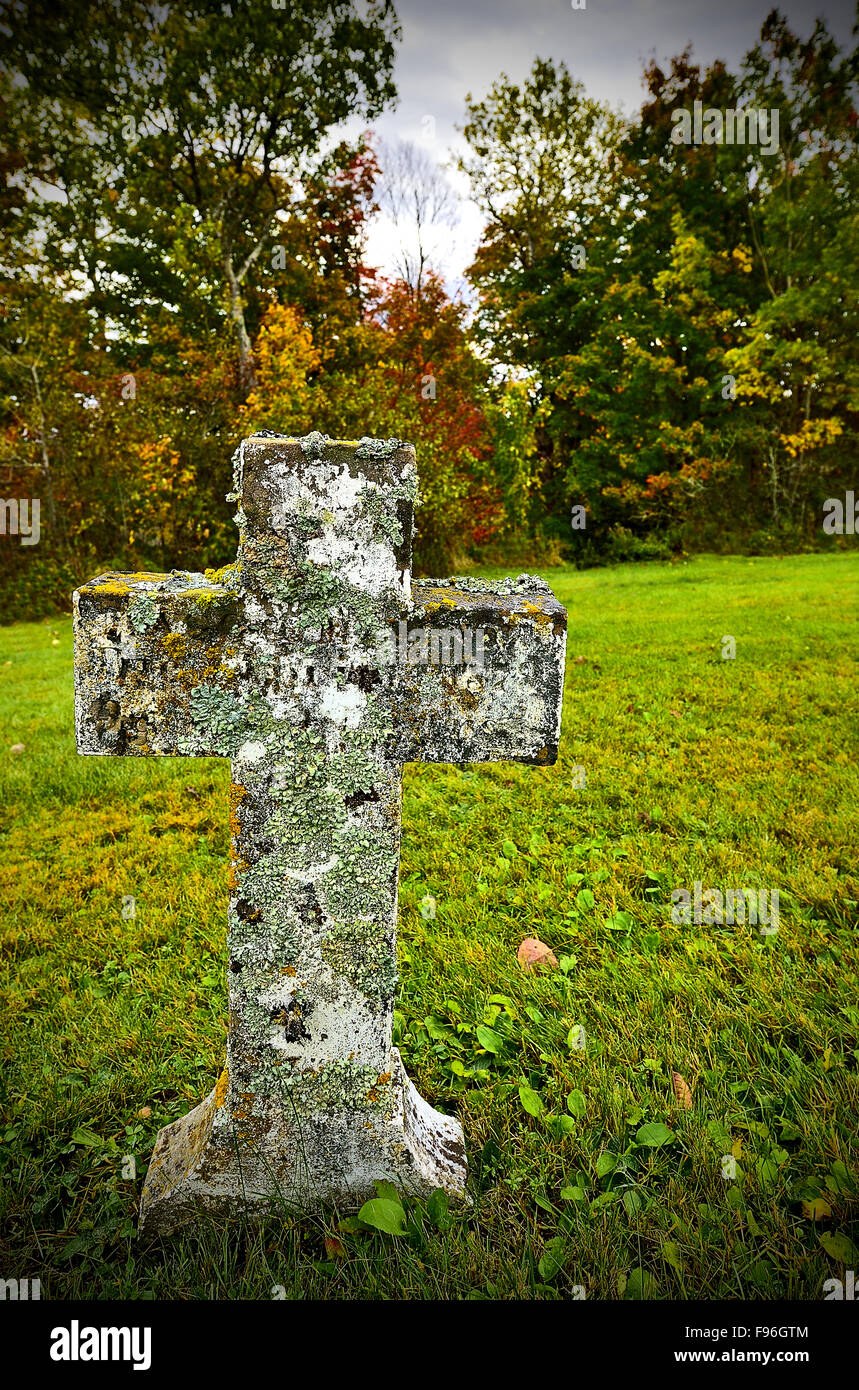 A vertical image of an old weathered stone cross in a graveyard near Sussex New Brunswick Canada. Stock Photo