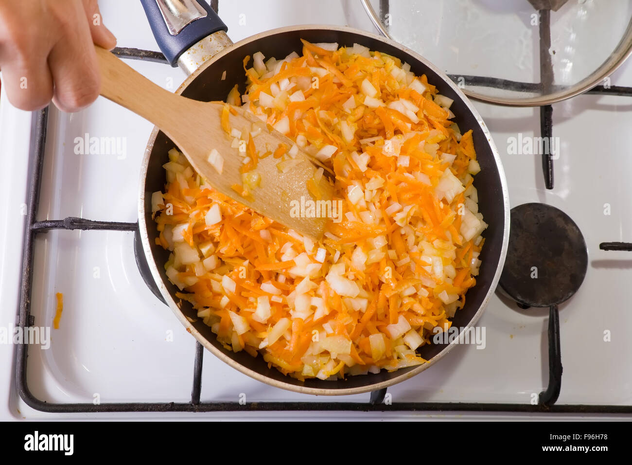 Closeup of roasting mixed onion and carrot on gas stove. One of the stages of preparation of the stuffed beef.  See series Stock Photo