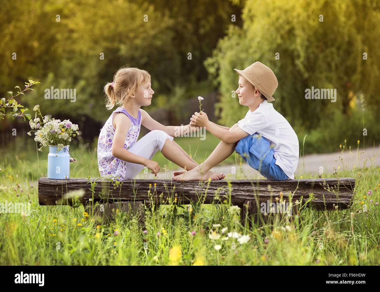 Cute boy and girl in love. They sitting on bench at sunset. Stock Photo