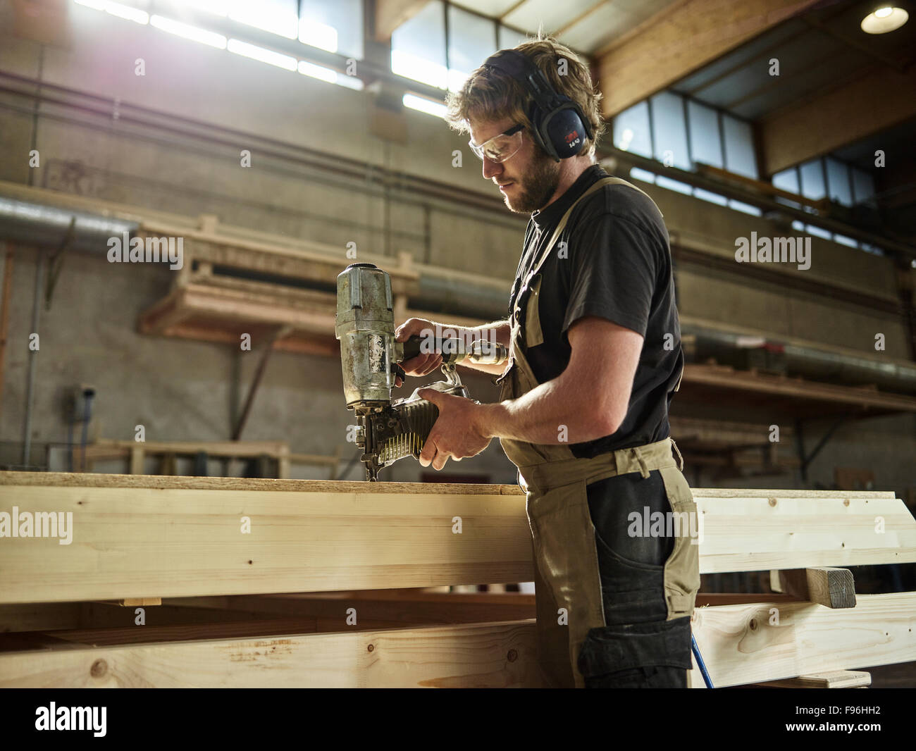 Carpenter nailing chipboard to a wooden beam, nail gun, timber frame construction, Austria Stock Photo