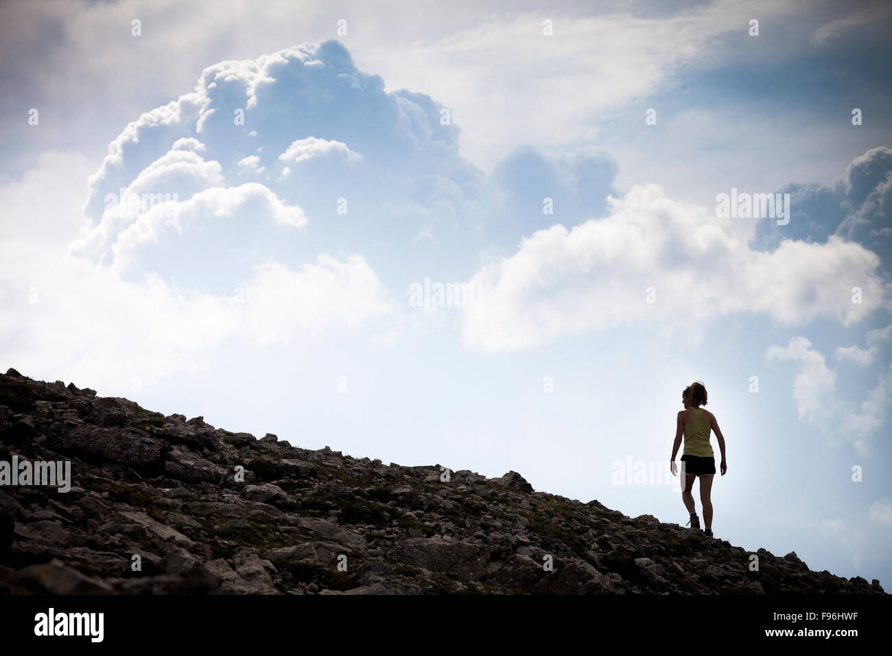A young woman hiking along the Sulphur Skyline silhouetted against storm clouds. Miette Hotsprings, Jasper National Park, Stock Photo