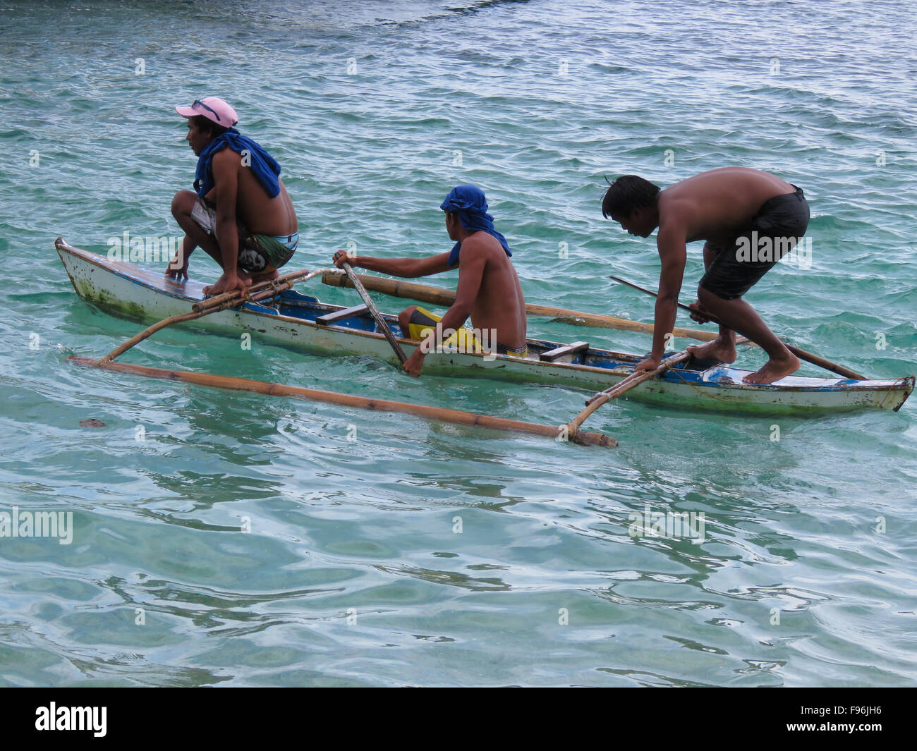 Three men and a small boat. Philippines. Stock Photo