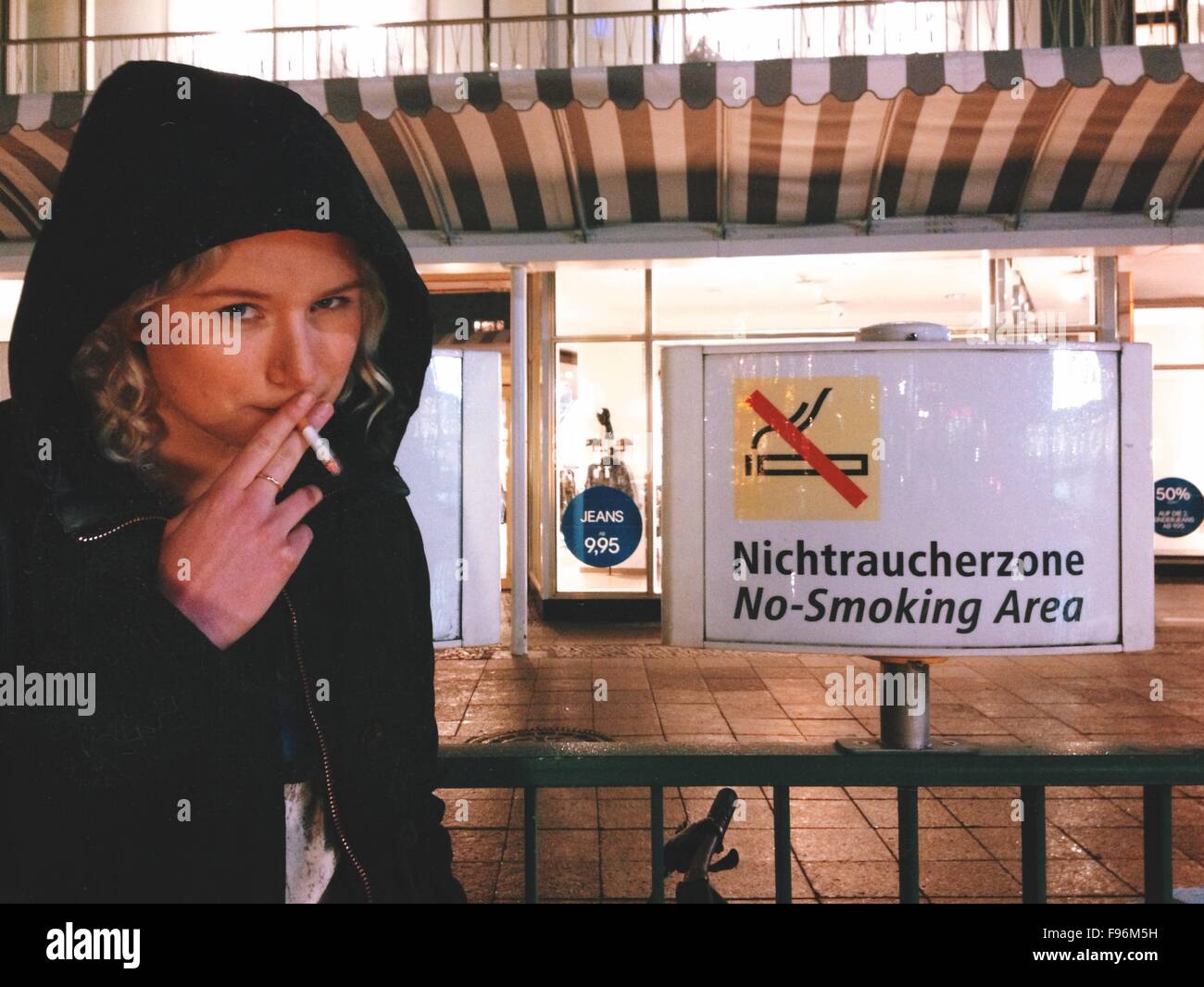 Young Woman Smoking In Front Of No Smoking Sign Stock Photo Alamy