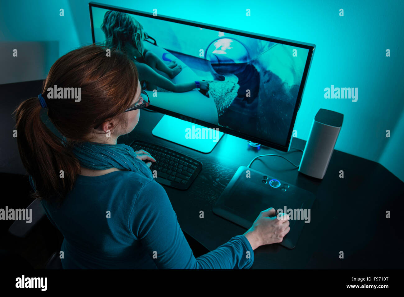 Woman (35) editing photography on a desktop PC in her home office. Stock Photo