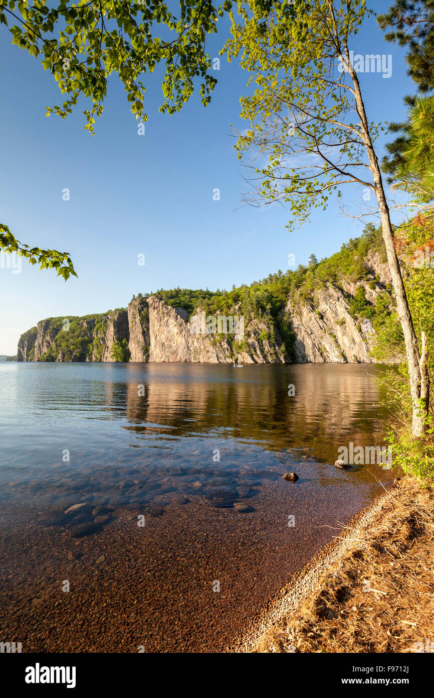 A blue canoe on Mazinaw Lake passes Mazinaw Rock in Bon Echo Provincial