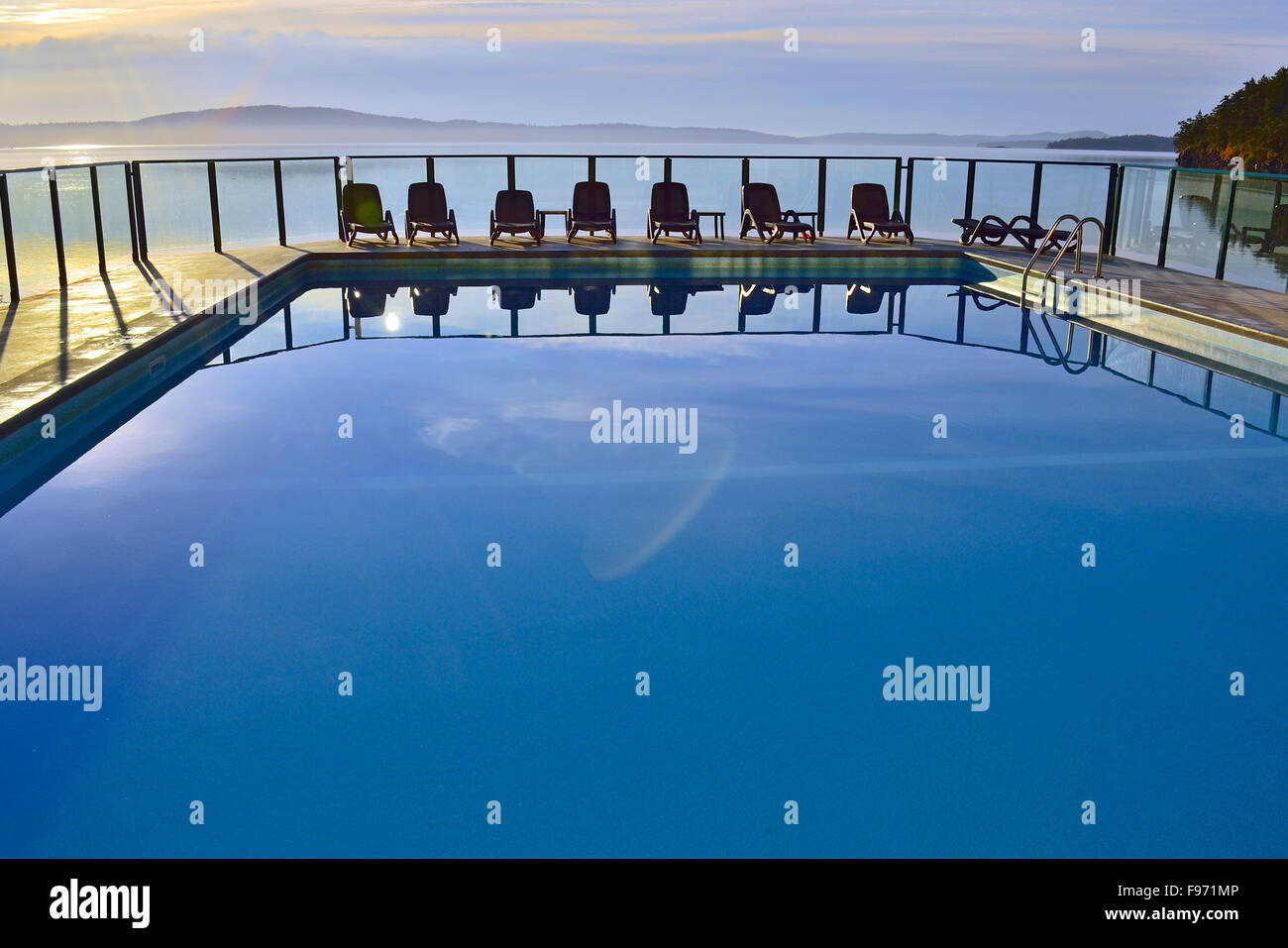 A horizontal image of an outdoor swimming pool with a line of chairs at ...