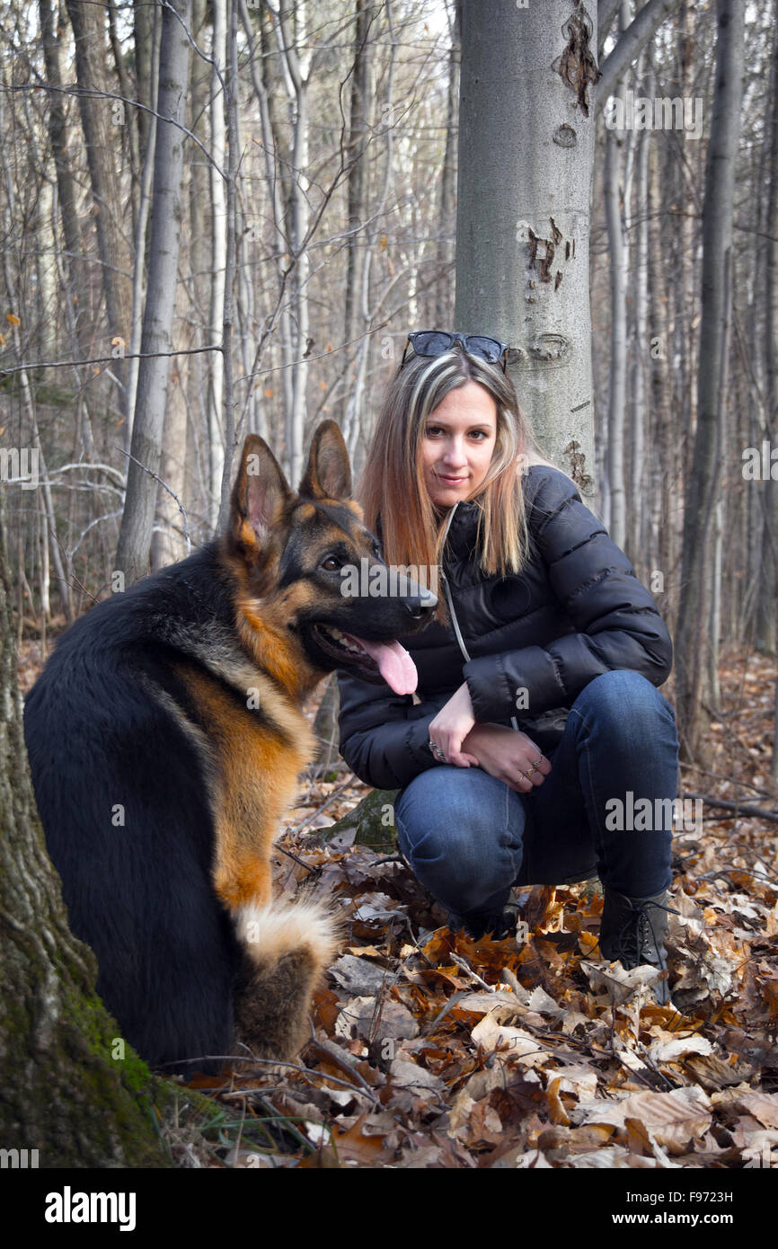 Young woman and a german shepherd dog outdoor in the forest after a walk Stock Photo