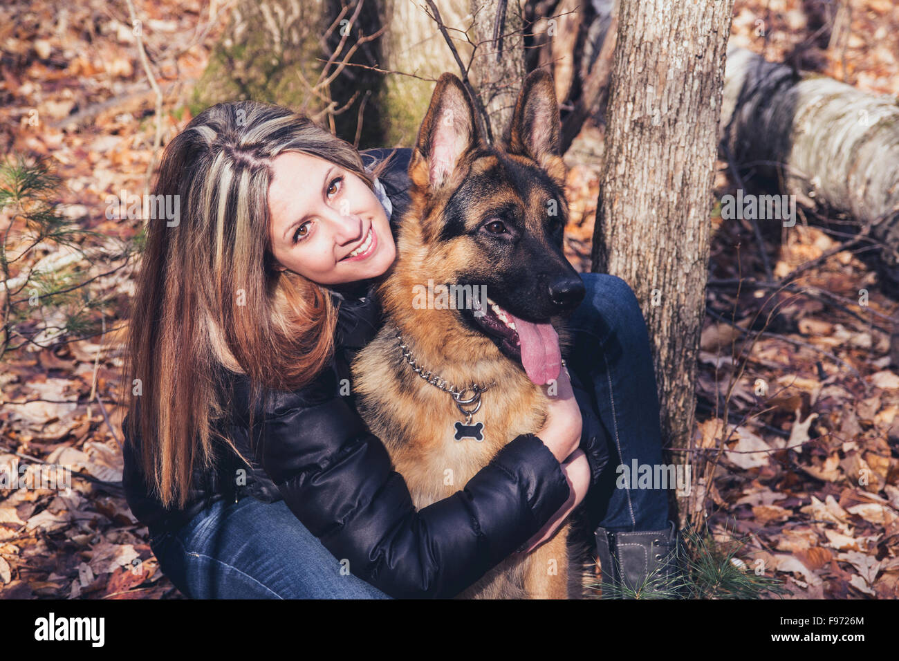 Young woman smiling with a german shepherd dog outdoor in the forest Stock Photo