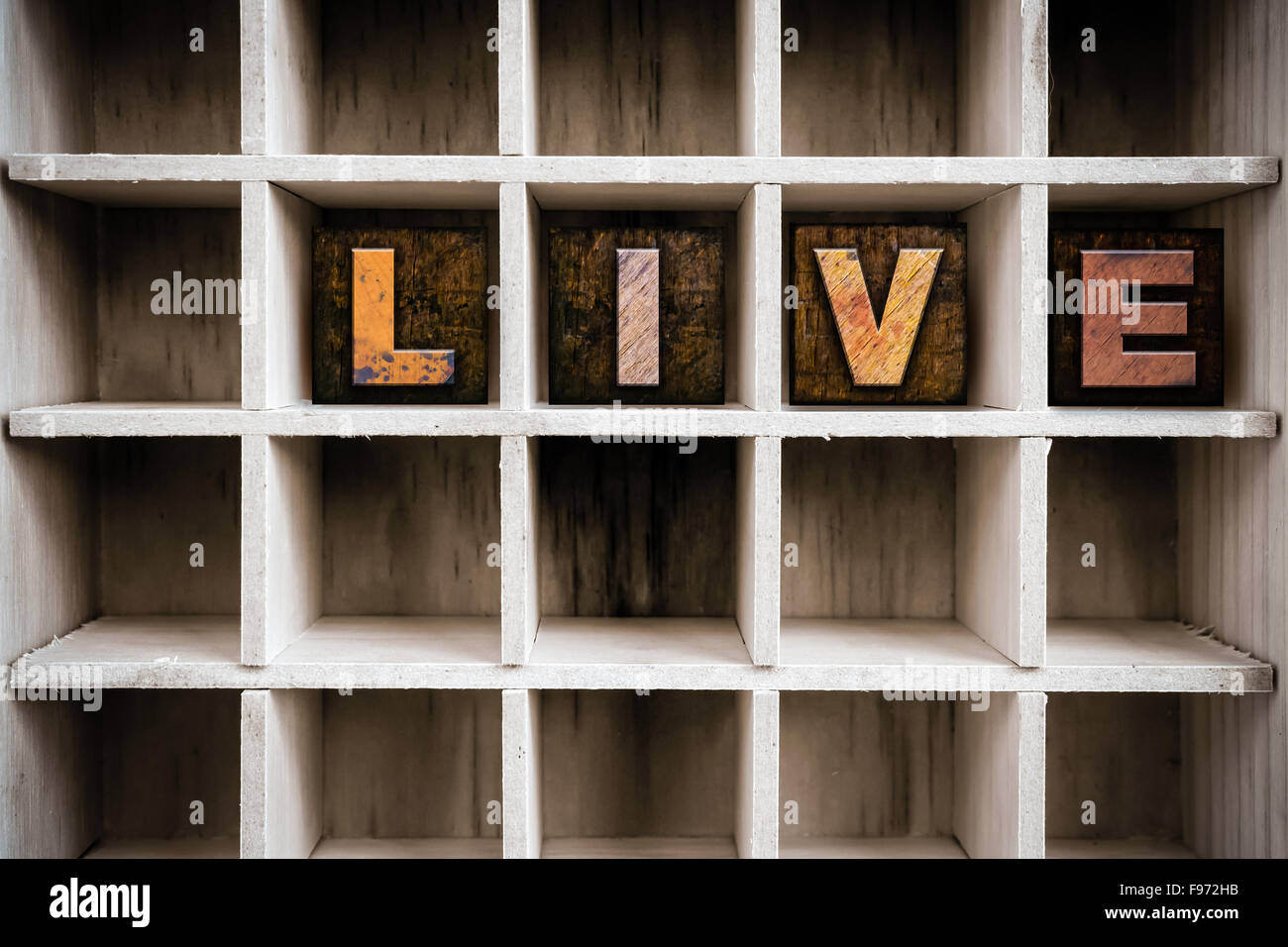 The word 'LIVE' written in vintage ink stained wooden letterpress type in a partitioned printer's drawer. Stock Photo