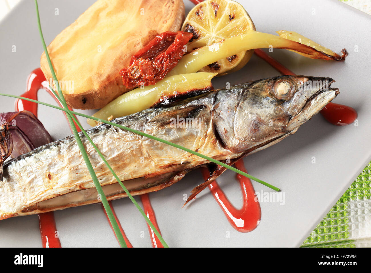 Roasted whole mackerel with potato and raspberry balsamic reduction Stock Photo