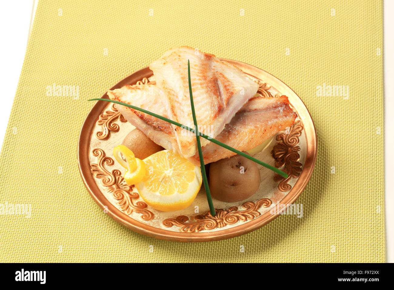 Pan fried fish fillets with new potatoes and lemon Stock Photo