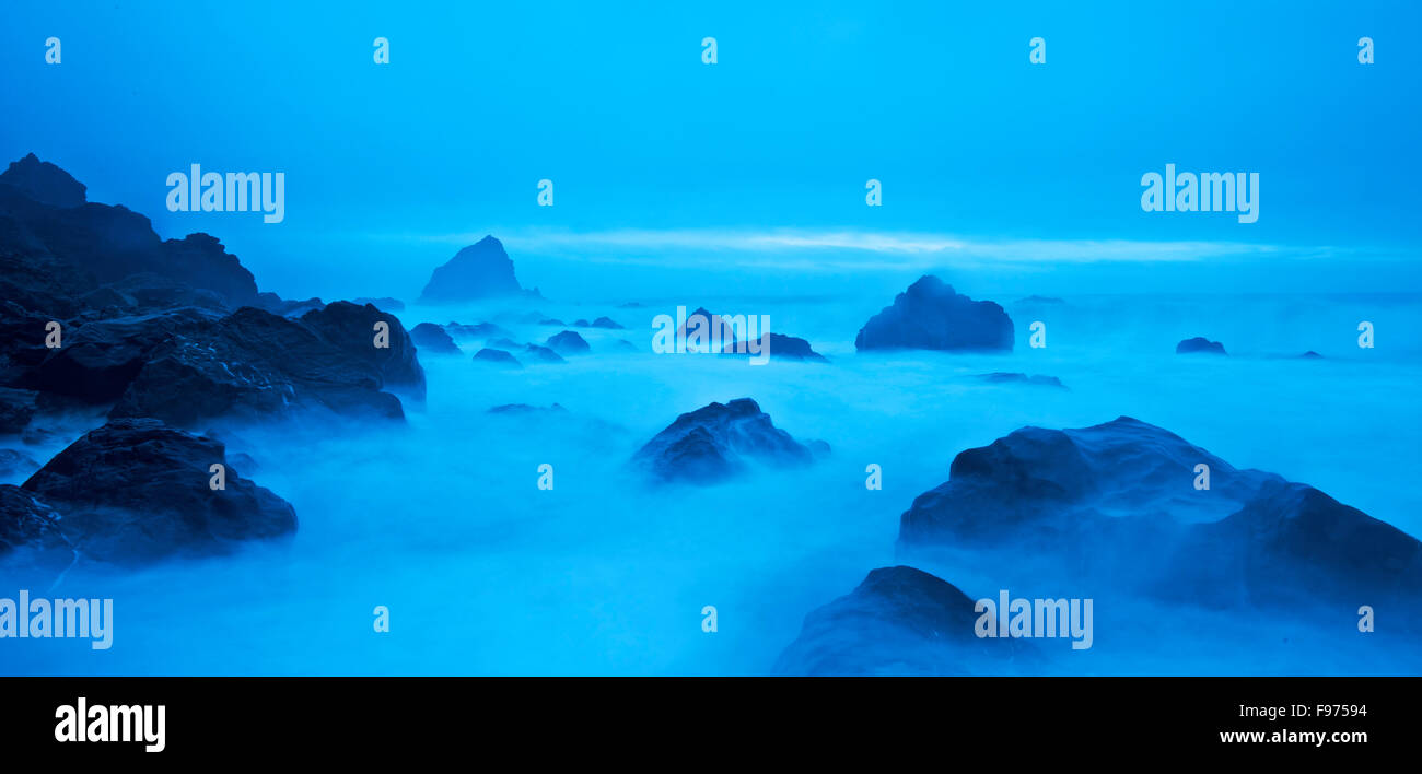 A panoramic view of water rushing over rocks on the Northern California shoreline at dusk. Stock Photo