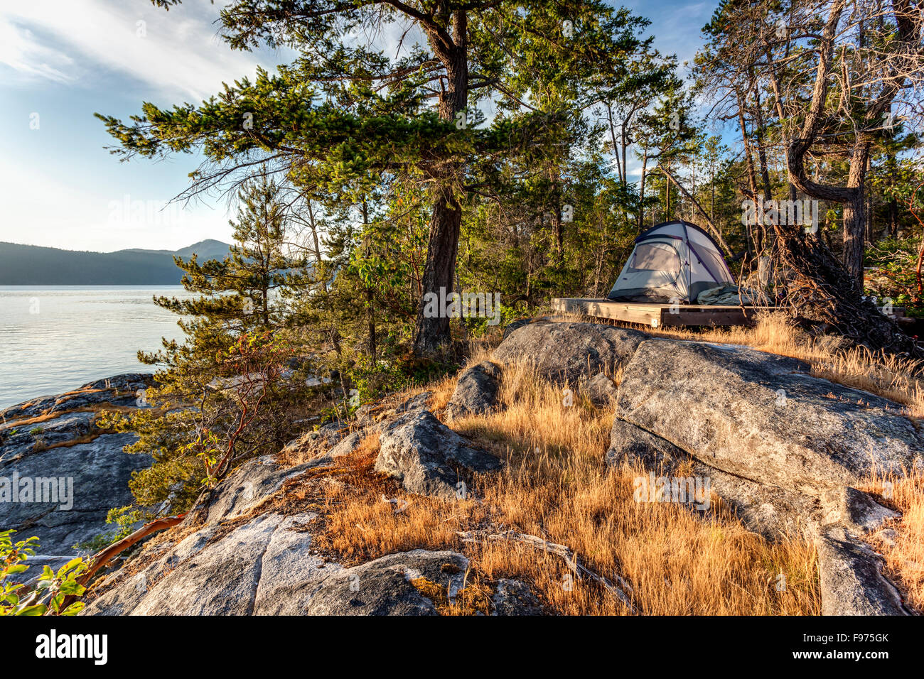 The sun sets on a kayaker's tent on West Curme Island in Desolation Sound Marine Park, British Columbia, Canada. Stock Photo