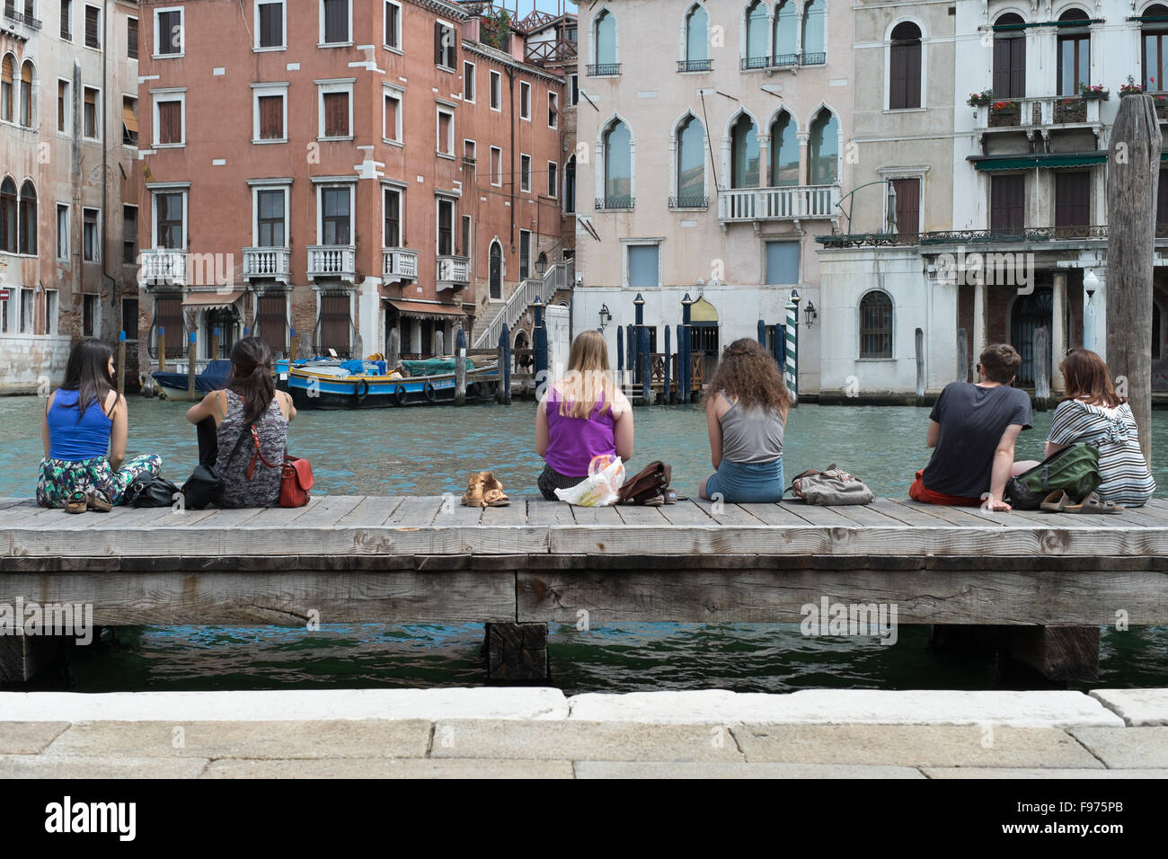 People Resting On Wood Pier Over Canal Stock Photo