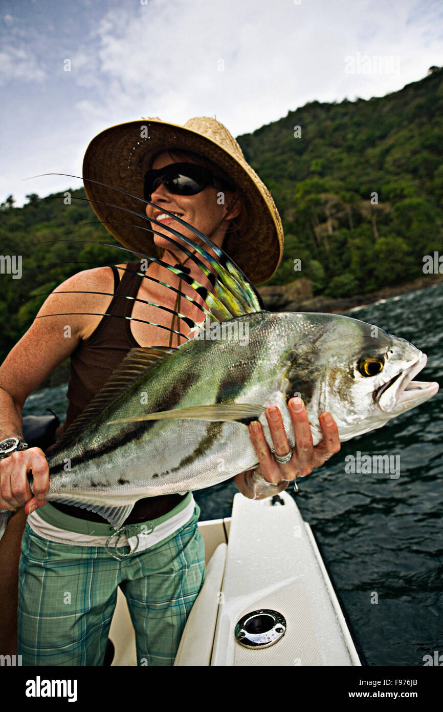A women fishing in sunglasses and straw hat holds up a freshly caught  rooster fish Stock Photo - Alamy
