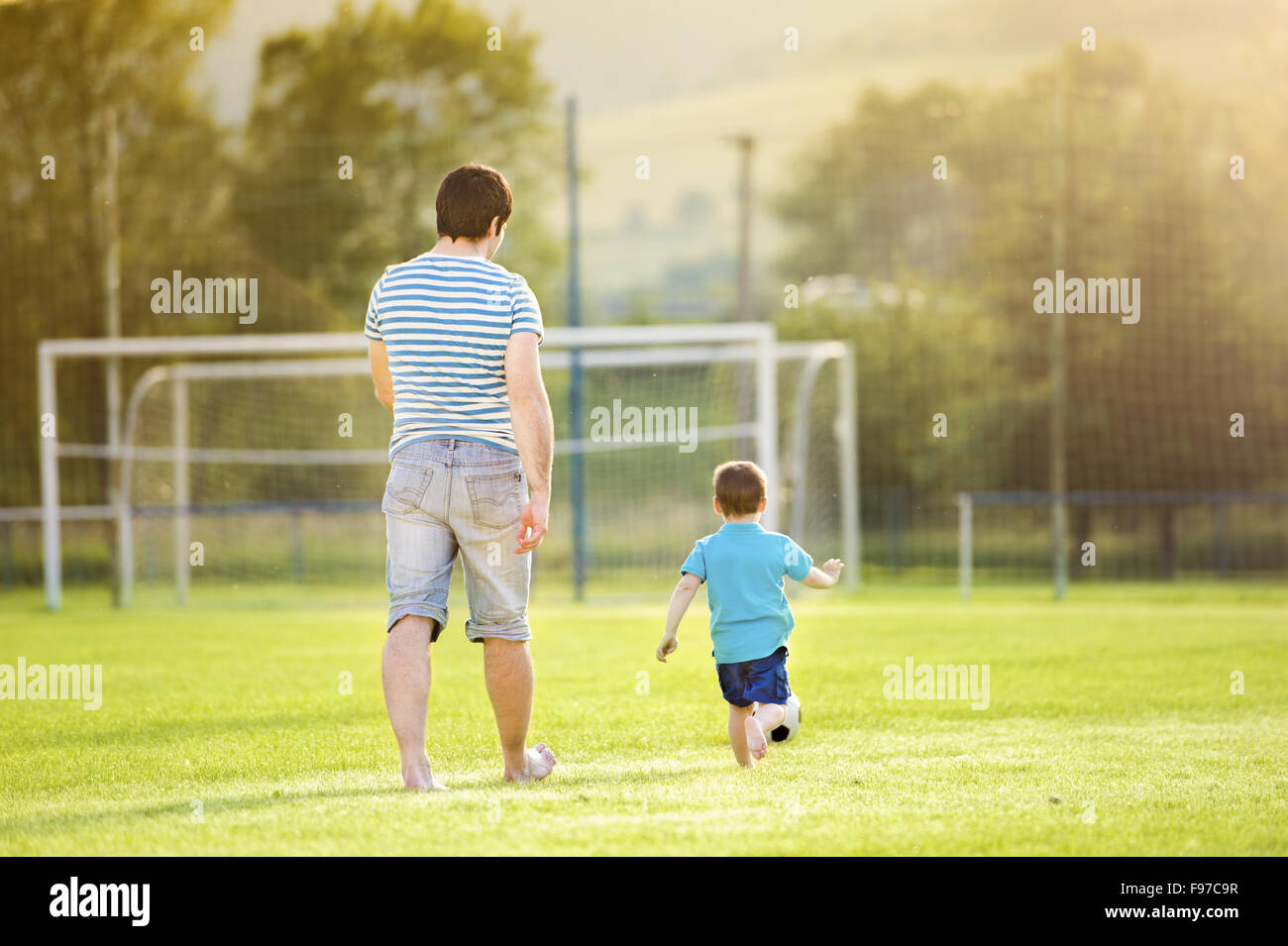 Young father with his little son playing football on football pitch Stock Photo