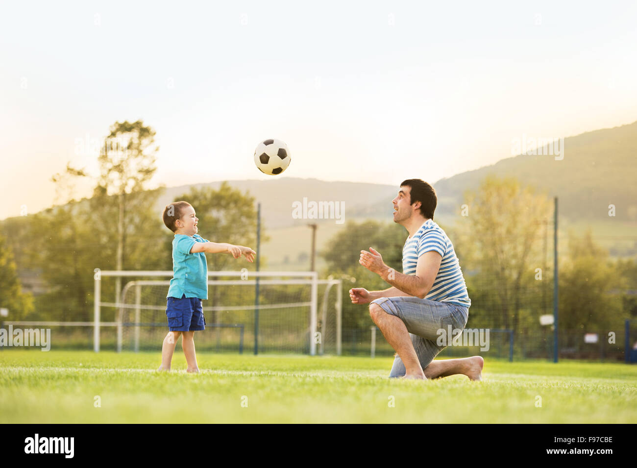 Young father with his little son playing football on football pitch Stock Photo